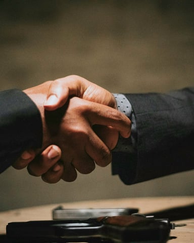 Two people shaking hands over a wooden table in a dark moody setting